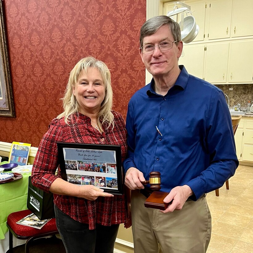 Woman and man standing holding a framed photo.