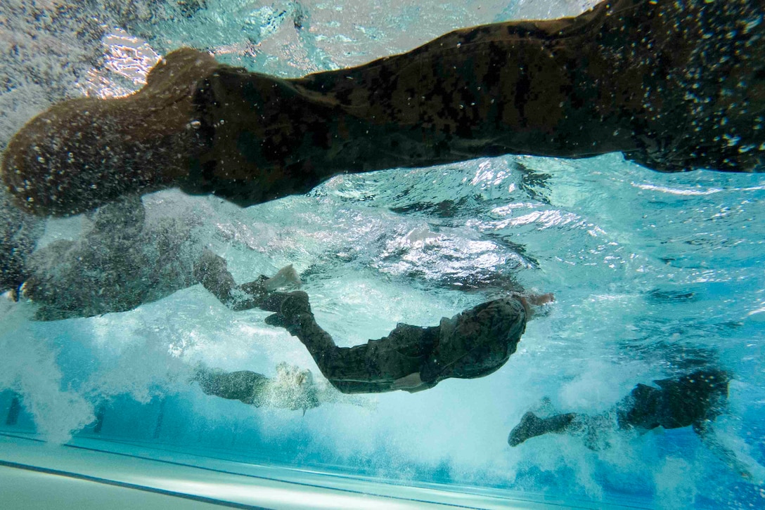 An underwater view of Marines swimming in a pool.