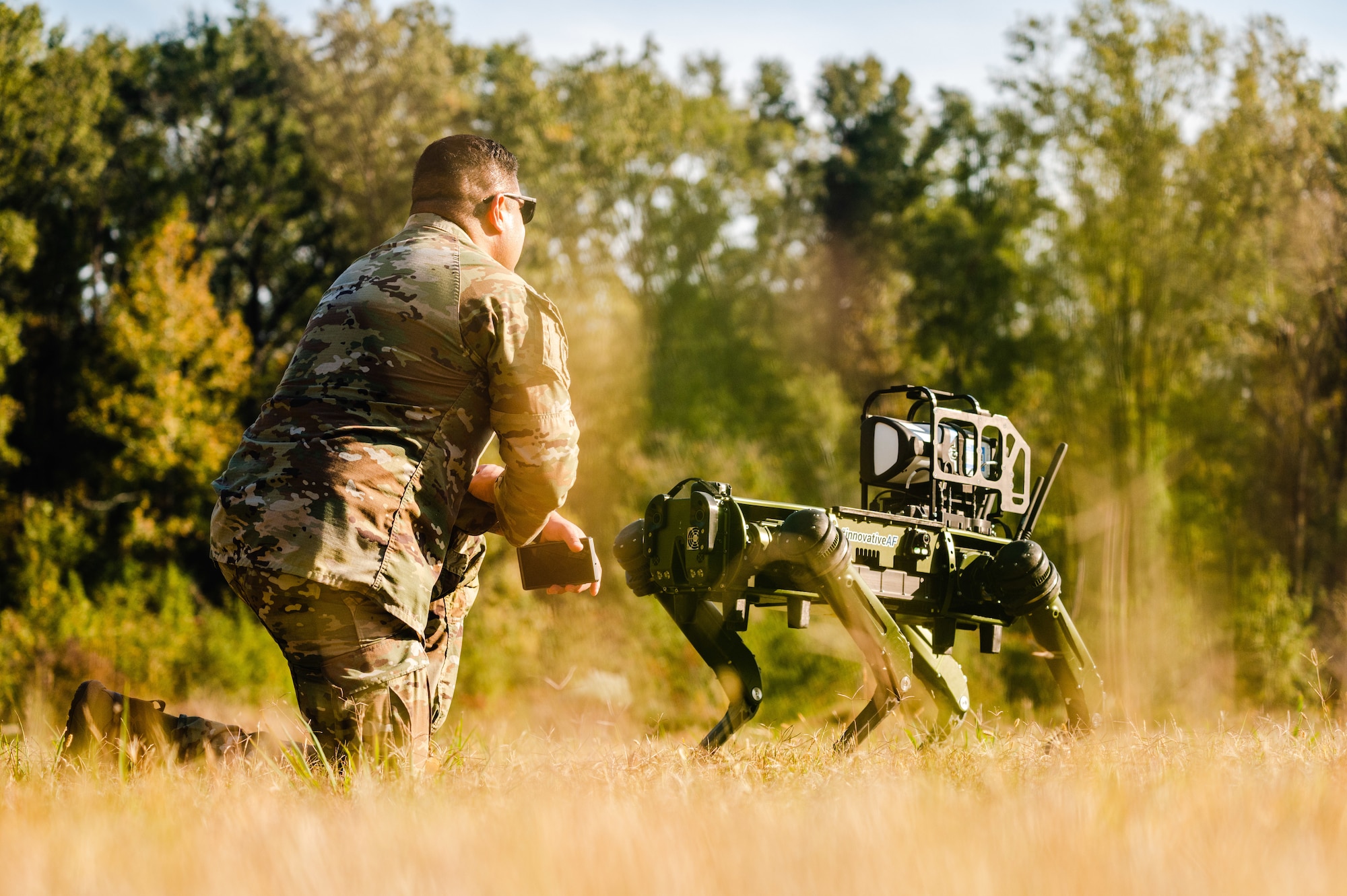 Airman kneels with robot dog