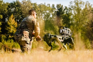 Airman kneels with robot dog