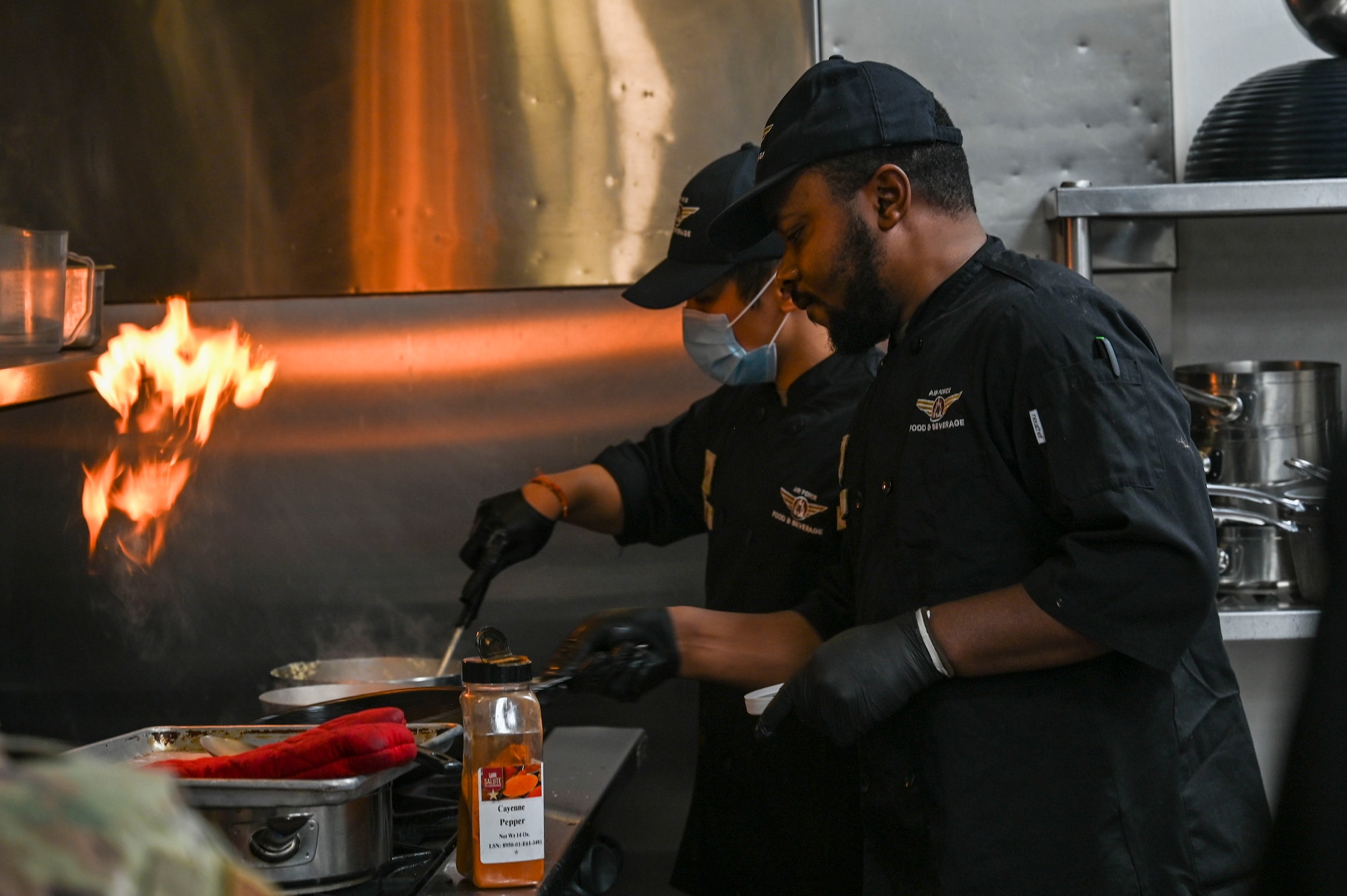 Airmen cook food on a stove.