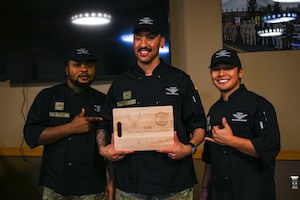 Airmen pose with an engraved cutting board.