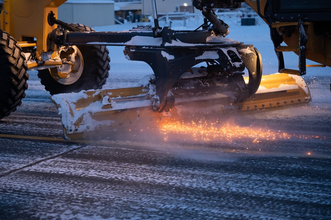 A road grader operator from the 354th Civil Engineering Squadron scraps ice off the flightline on Eielson Air Force Base, Alaska, Dec. 19, 2023. The road grader operators run 24/7 shifts to ensure the flightline is clear for aircraft to travel anywhere in the Northern Hemisphere.  (U.S. Air Force photo by Airman Spencer Hanson)