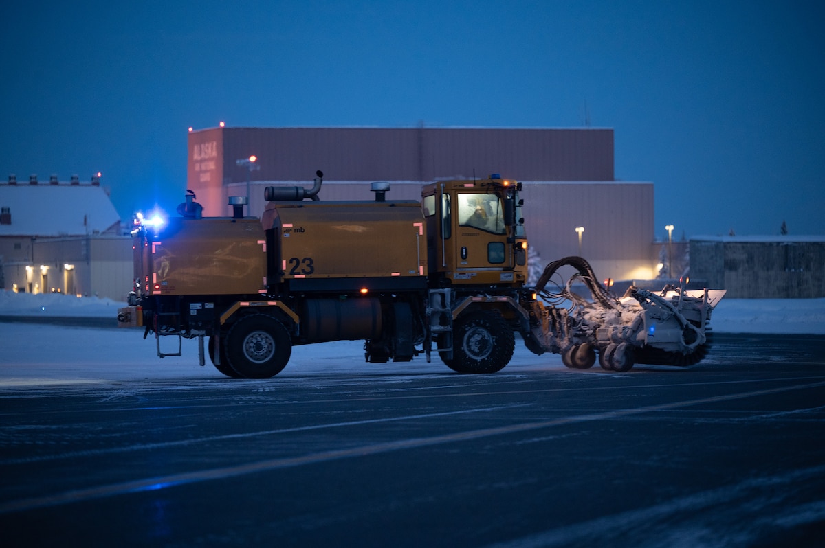 A snow broom operator from the 354th Civil Engineering Squadron plows snow off of the flightline on Eielson Air Force Base, Alaska, Dec. 19, 2023. The snow broom operators run 24/7 shifts to ensure the flightline is clear for aircraft to travel anywhere in the Northern Hemisphere.  (U.S. Air Force photo by Airman Spencer Hanson)