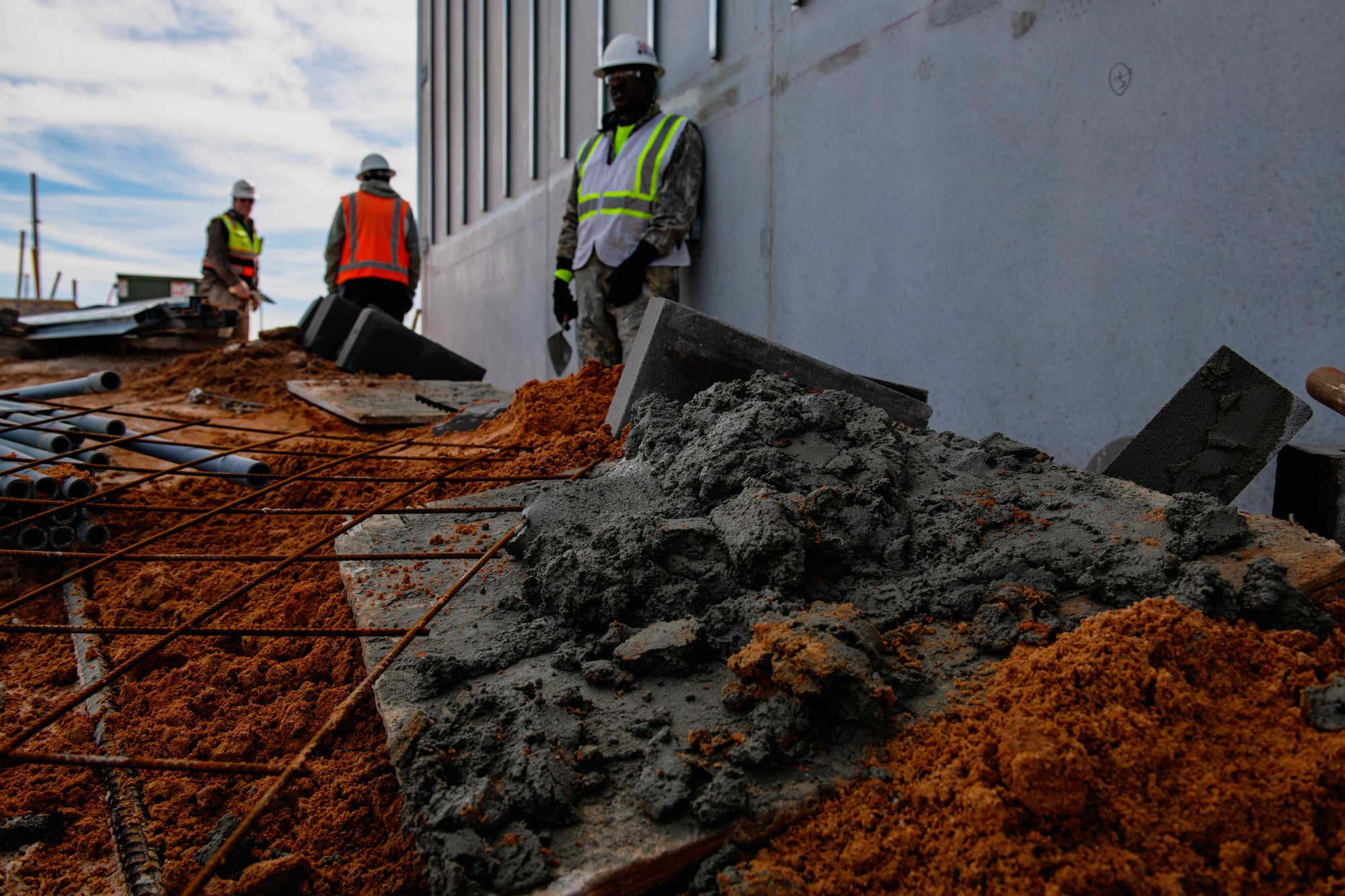 Construction worker spreads cement onto building.