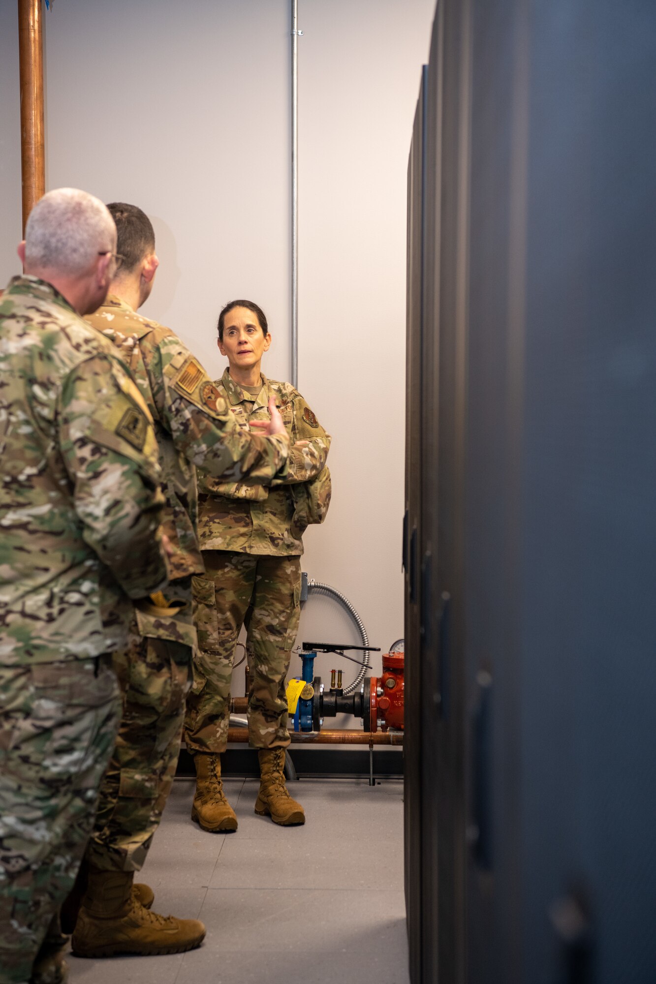 Three Airmen standing in server room.