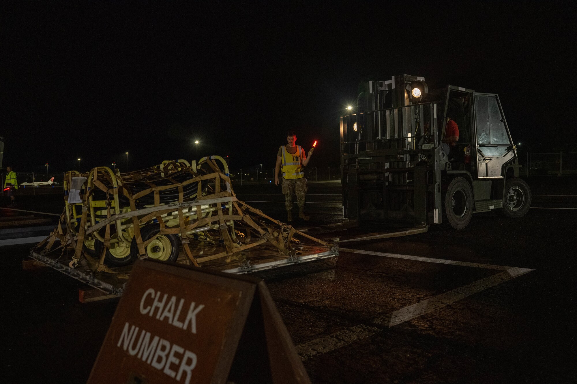 2nd. Lt. Shane Fillion, 647th Logistics Readiness Squadron, cargo deployment functional officer, directs a forklift carrying cargo onto a K-loader during the Readiness Exercise 24-01 at Joint Base Pearl Harbor-Hickam, Hawaii, Dec. 13, 2023. The 15th Wing trains to operate, fight and advance its capabilities through realistic training exercises designed to test and develop joint logistics, resilience and rapid strategic mobility. (U.S. Air Force photo by Senior Airman Makensie Cooper)