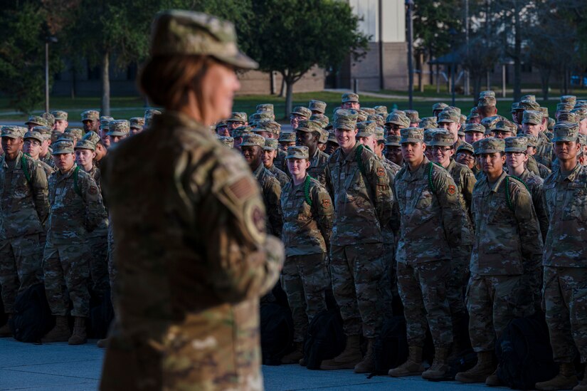 An airman speaks in front of a group of airmen standing in formation.