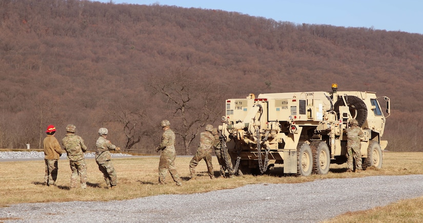 Soldiers prepare to recover a vehicle that is mired (stuck) in a sand pit. Regional training Site Maintenance – Fort Indiantown Gap, under the 94th Training Division, partnered with the 1st Brigade Combat Team 10th Mountain Division in Fort Drum, NY, to ensure 16 active-duty soldiers received the wheeled recovery specialist additional skill identifier.
