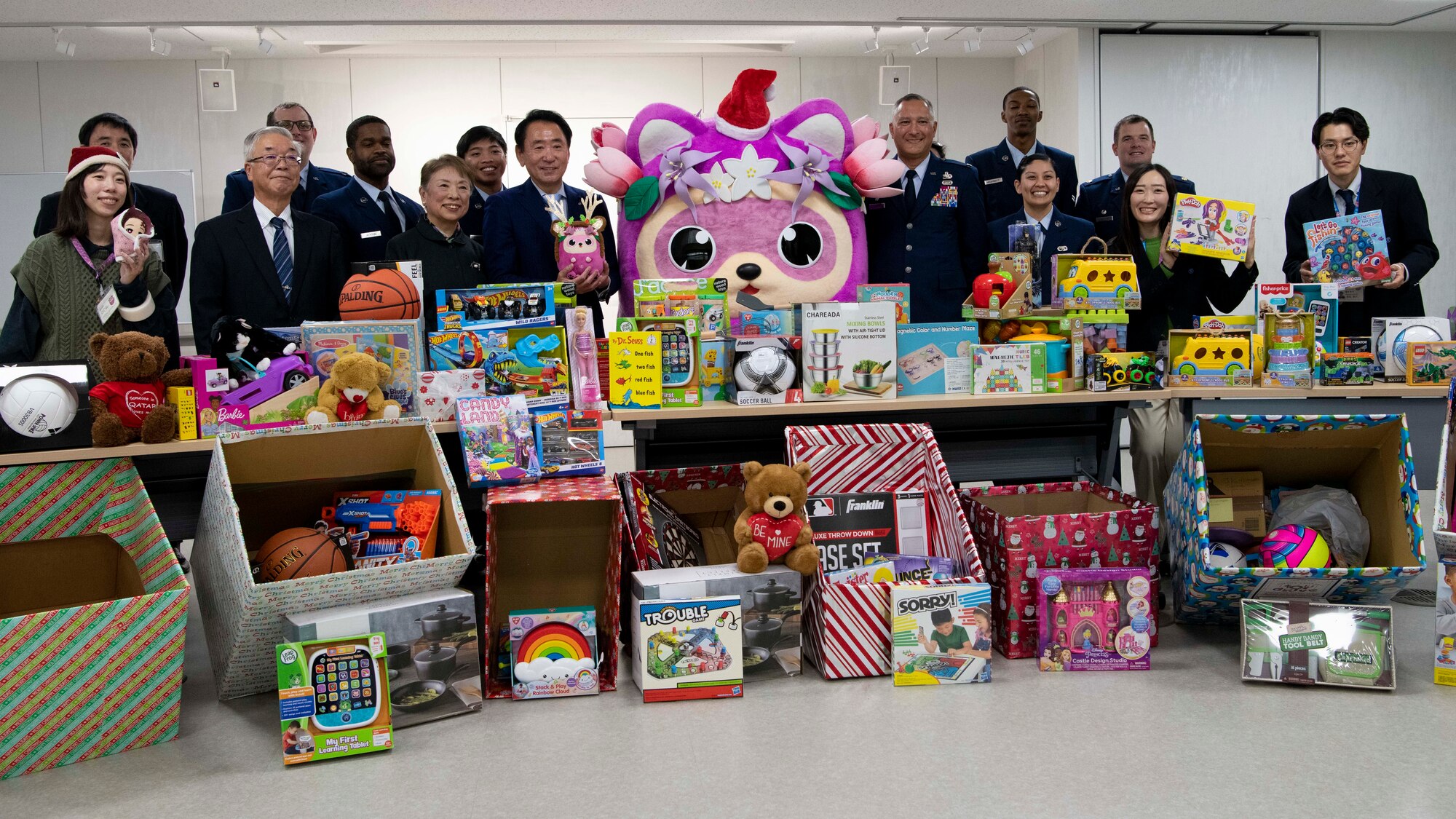 Airmen and Japanese nationals pose for a photo in front of a table of gifts.