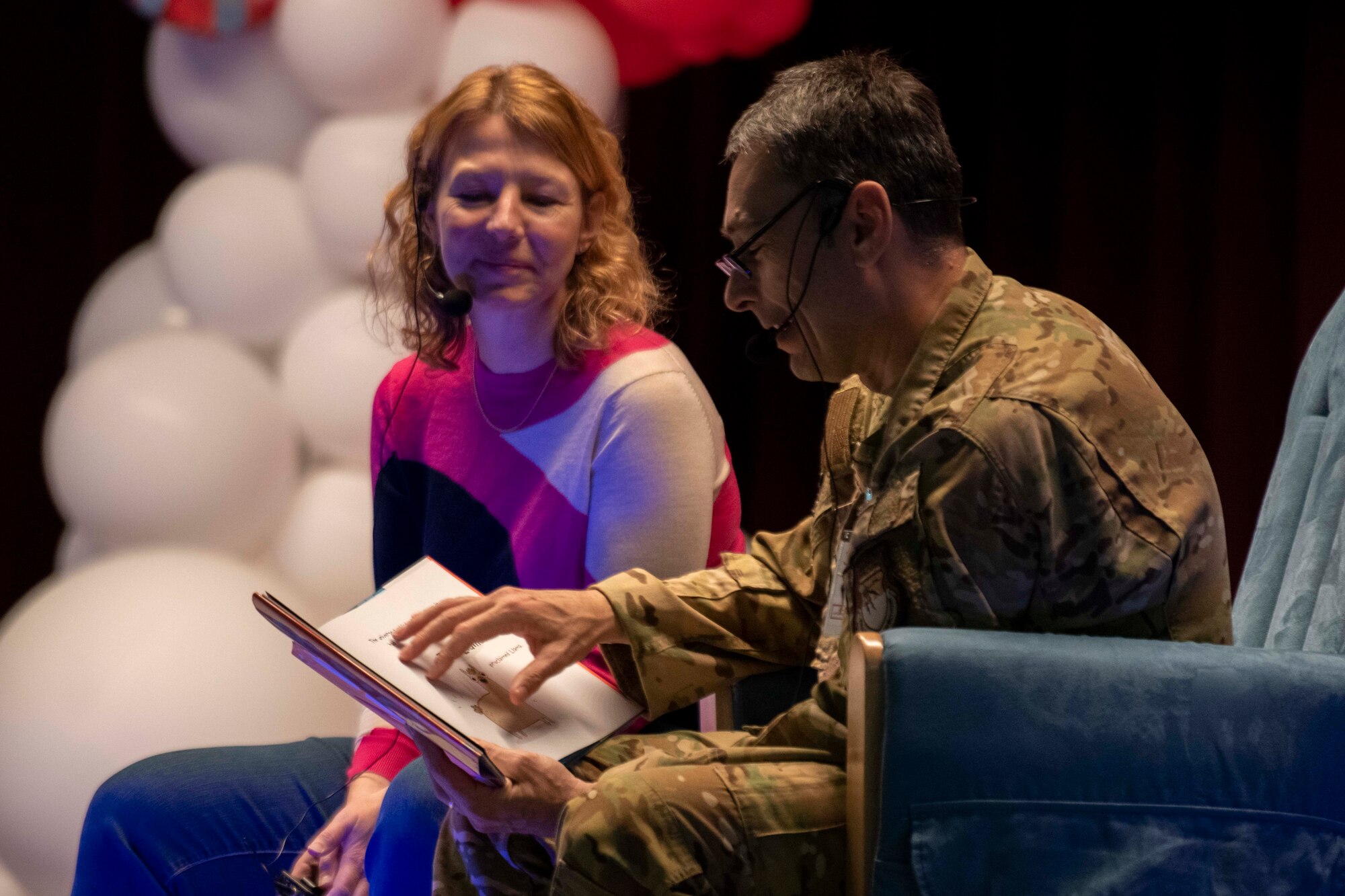 A military man and a woman read a book.