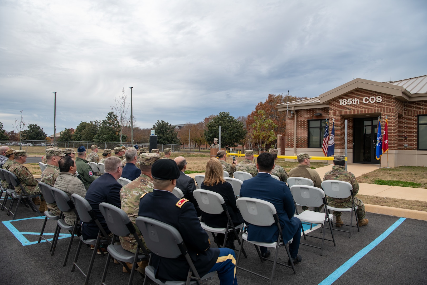 Group of military and civilians sitting in audience for outdoor ceremony.