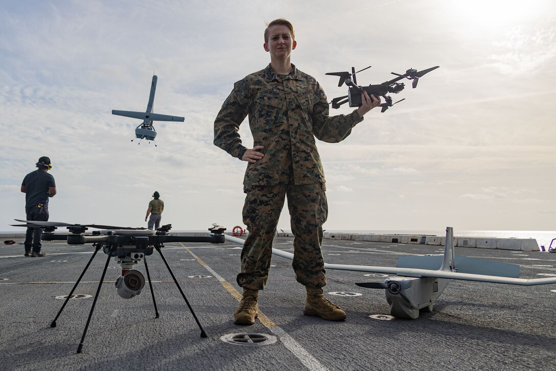 U.S. Marine Corps Sgt. Gracelyn Oldham, an unmanned aerial vehicle (UAV) operator with the Battalion Landing Team 1/6, 26th Marine Expeditionary Unit (Special Operations Capable) (MEU(SOC)) poses for a picture alongside multiple UAV systems while on the flight deck aboard the San Antonio-class amphibious transport dock ship USS Mesa Verde (LPD 19), Mediterranean Sea, Nov. 10, 2023.



Oldham is the only female UAV operator with Battalion Landing Team 1/6, 26th MEU(SOC) and will soon be the first in her Military Occupation Specialty to fly every group of drone systems. A native of Bluefield, West Virginia, she moved constantly having missionary parents, living in Michigan, Indiana, Illinois, Alabama, Tennessee, and Egypt are just a few of the locations she has resided.



U.S. Marines and Sailors of the 26th Marine Expeditionary Unit (Special Operations Capable), embarked on the ships of the Bataan Amphibious Ready Group, are on a scheduled deployment as the Tri-Geographic Combatant Command crisis response force with elements deployed to the U.S. 5th Fleet and U.S. 6th Fleet areas of operation to increase maritime security and stability, and to defend U.S., Allied, and Partner interests. (U.S. Marine Corps photo by Cpl. Michele Clarke)