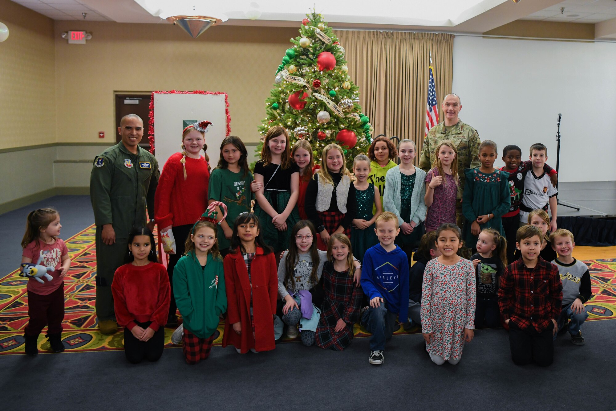 A group of kids pose for a photo with military members.