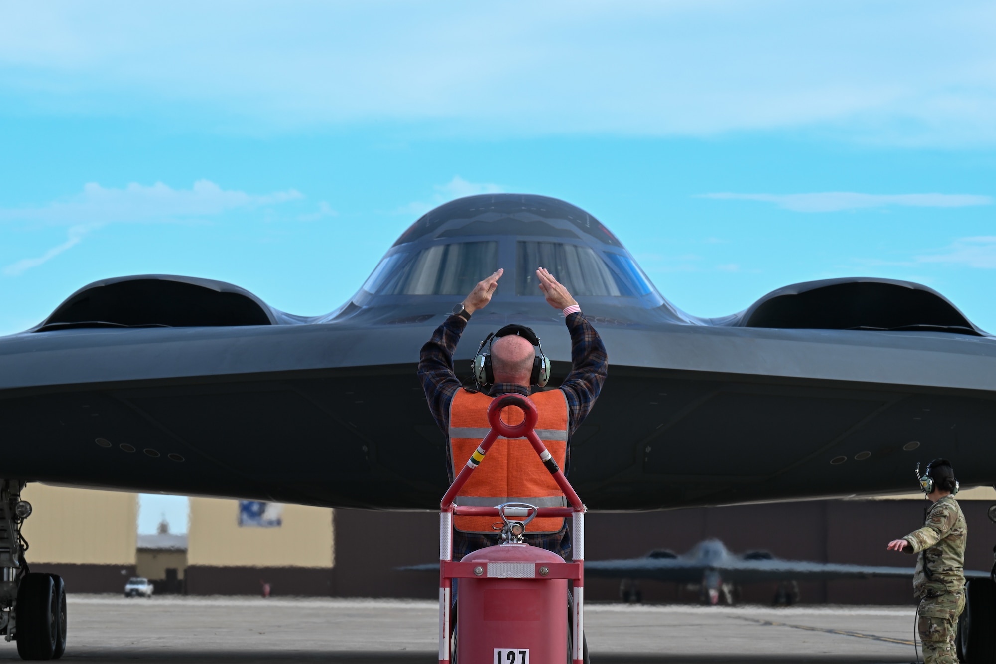 Retired U.S. Air Force Senior Master Sgt. Keith Meadows marshals the B-2 Spirit stealth bomber at Whiteman Air Force Base, Mo., Dec. 15, 2023. As a Staff Sgt. at the time, Keith was the first crew chief to marshal in the B-2 30 years ago when it first arrived at Whiteman AFB. (U.S. Air Force photo by Airman 1st Class Matthew S. Domingos)