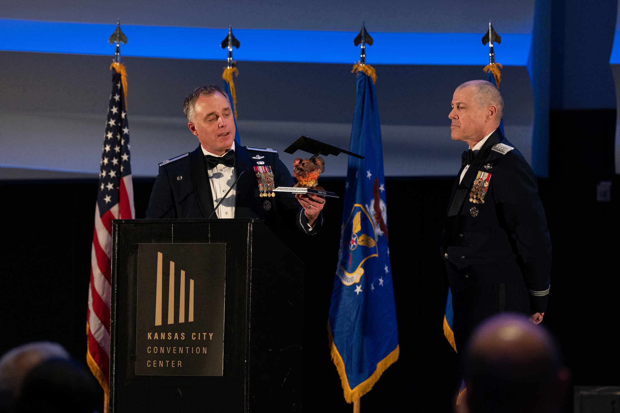 U.S. Air Force Col. Keith Butler, 509th Bomb Wing commander, presents Gen. Thomas Bussiere, Air Force Global Strike Command commander, with a B-2 Spirit stealth bomber figure at Kansas City, Mo., Dec. 15, 2023. The first aircraft, Spirit of Missouri, was delivered Dec. 17, 1993. (U.S. Air Force photo by Airman 1st Class Robert E. Hicks.)