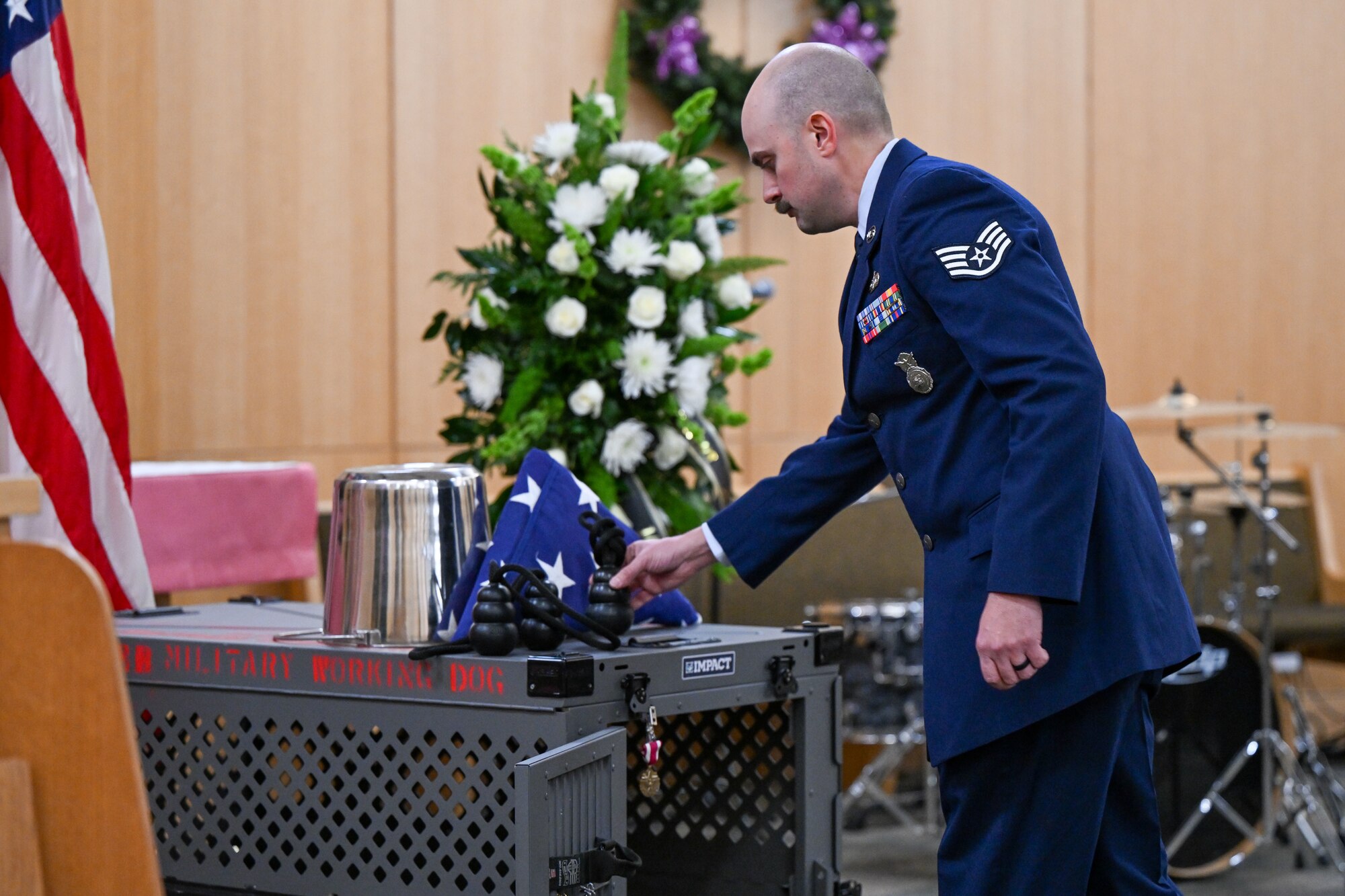 An Airman lays a toy on the missing dog display during a MWD memorial