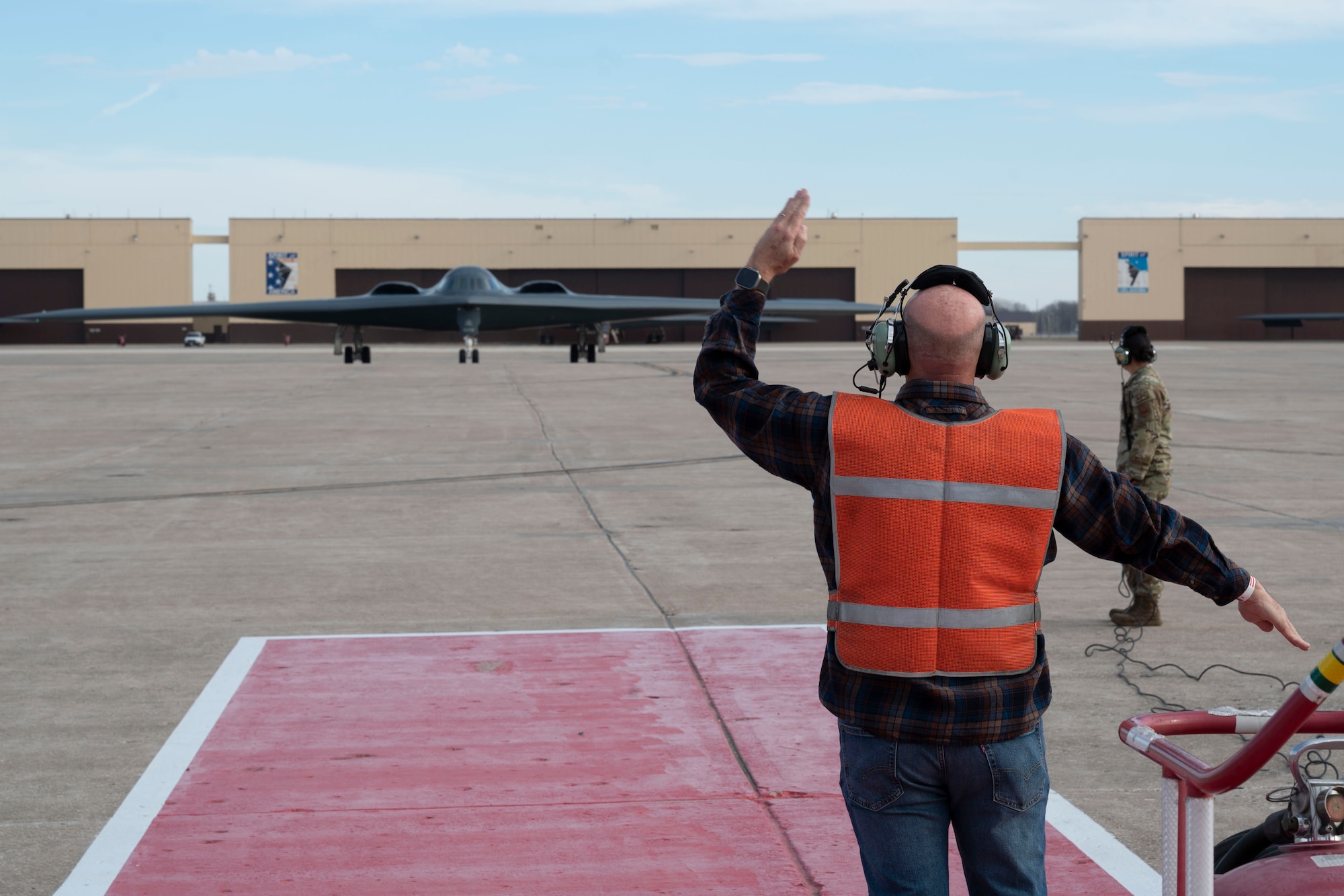 Retired U.S. Air Force Senior Master Sgt. Keith Meadows, marshals in a B-2 Spirit stealth bomber during a ceremony at Whiteman Air Force Base, Mo., Dec. 15, 2023. As a Staff Sgt. at the time, Meadows marshalled the B-2 for its first arrival to Whiteman AFB, 30 years ago and performed the same duties during a ceremony honoring that anniversary. (U.S. Air Force photo by Tech. Sgt. Anthony Hetlage)