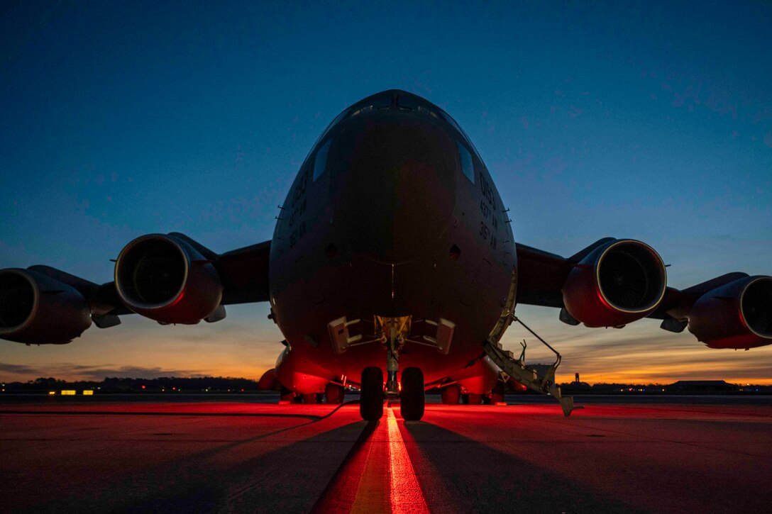 Red light shines on a parked aircraft at night.