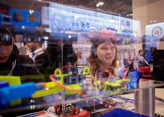 Students from For Inspiration and Recognition of Science and Technology (FIRST) Robotics teams view education and workforce development technologies from the Office of the Secretary of Defense Manufacturing Technology Program on display at the Defense Manufacturing Conference, Nashville, Tennessee Dec. 12, 2023. (DOD Photo by Jessica L. Dowell)