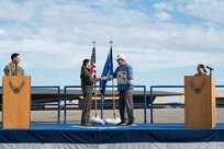 Retired U.S. Air Force Lt. Col. Bruce Hinds, B-2 Spirit test pilot, Spirit 1, hands a coin to Capt. Janel Campbell, 13th Bomb Squadron, Spirit 823, as part a ceremony reenacting the first arrival of the B-2 to Whiteman Air Force Base 30 years ago at Whiteman Air Force Base, Mo., Dec. 15, 2023. Hinds was the chief test pilot on the Advanced Technology Bomber program which led him to becoming the first person to fly the B-2 and having the Spirit number 1, a number that is given to each person who flies in the B-2. (U.S. Air Force photo by Tech. Sgt. Anthony Hetlage)