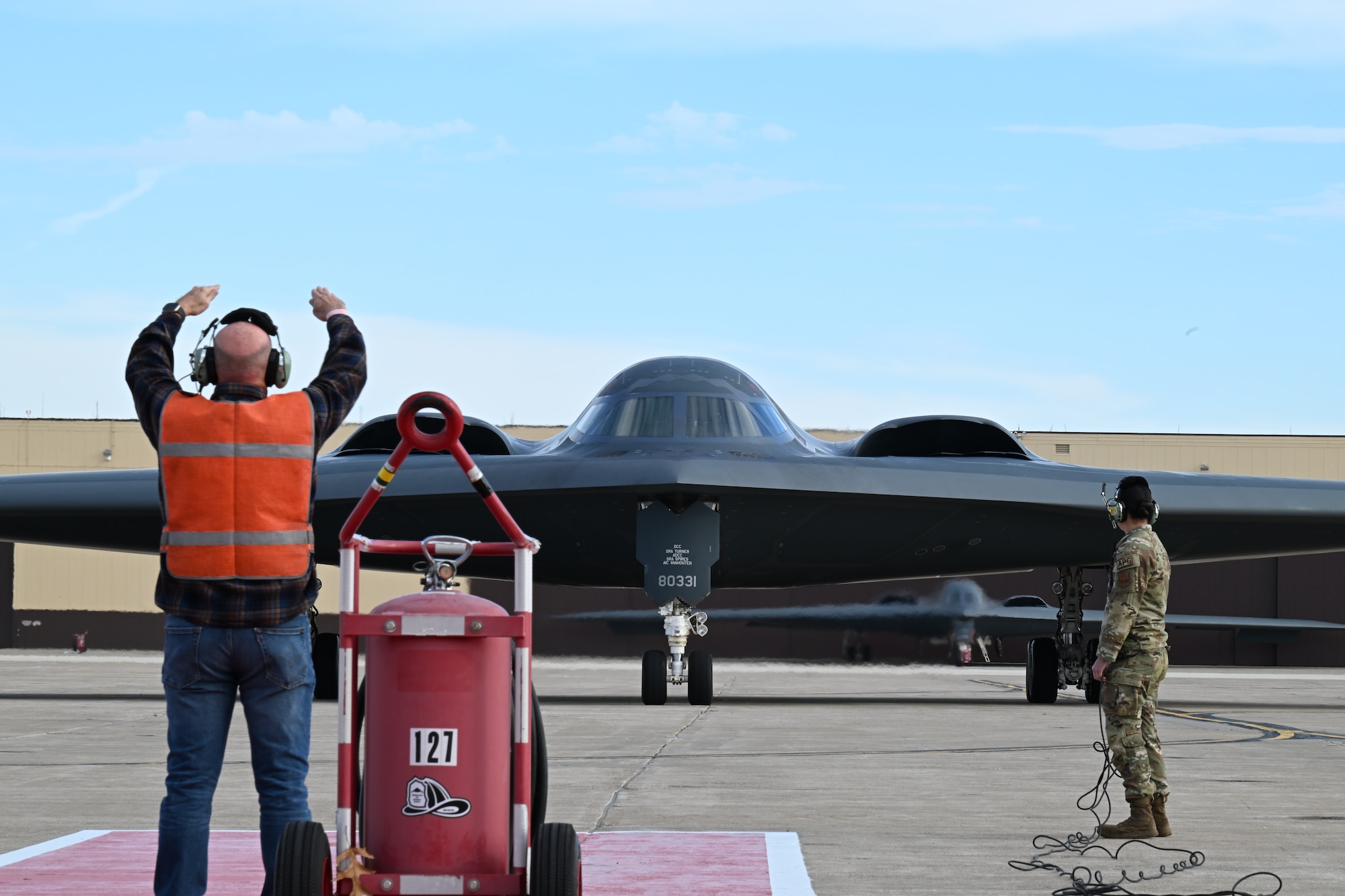 Retired U.S. Air Force Senior Master Sgt. Keith Meadows marshals the B-2 Spirit stealth bomber at Whiteman Air Force Base, Mo., Dec. 15, 2023. As a Staff Sgt. at the time, Keith was the first crew chief to marshal in the B-2 30 years ago when it first arrived at Whiteman AFB. (U.S. Air Force photo by Airman 1st Class Matthew S. Domingos)
