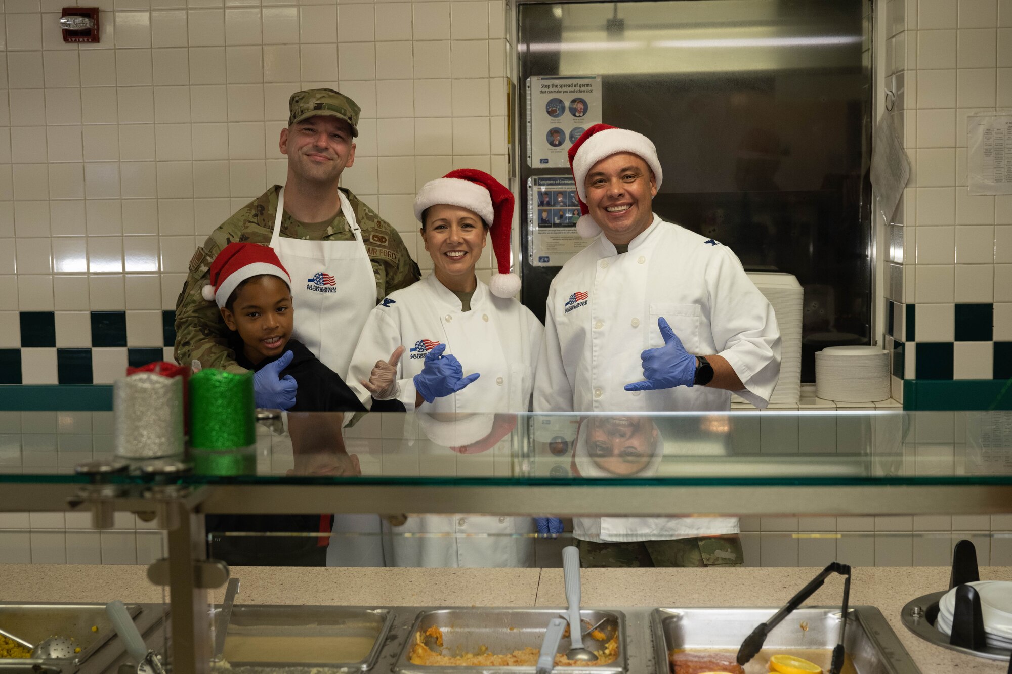 Leadership and family from the 15th Medical Group pose for a photo during a Christmas Eve lunch at the Hale Aina Dining Facility on Joint Base Pearl Harbor-Hickam, Hawaii, Dec. 24, 2023.  Leaders from the 15th Wing, 515th Air Mobility Wing and 647th Air Base Group attended the event to serve Airmen and their families lunch on Christmas Eve. (U.S. Air Force photo by Senior Airman Makensie Cooper)
