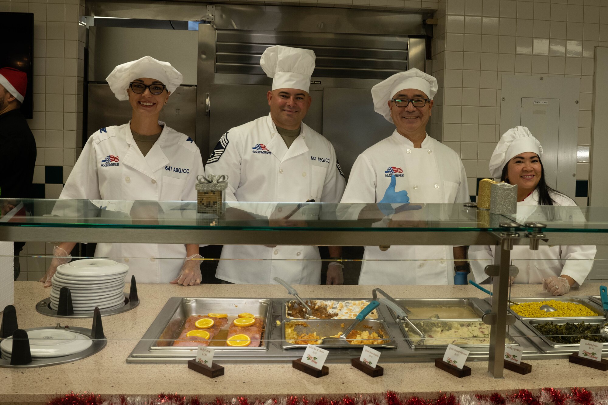 Air Force leadership and volunteers serve Christmas Eve lunch to Airmen and families at the Hale Aina Dining Facility on Joint Base Pearl Harbor-Hickam, Hawaii, Dec. 24, 2023. The 647th Force Support Squadron hosted the lunch for several JBPHH personnel and families to ensure those who were not able to travel home during the holiday season still enjoyed a holiday meal. (U.S. Air Force photo by Senior Airman Makensie Cooper)