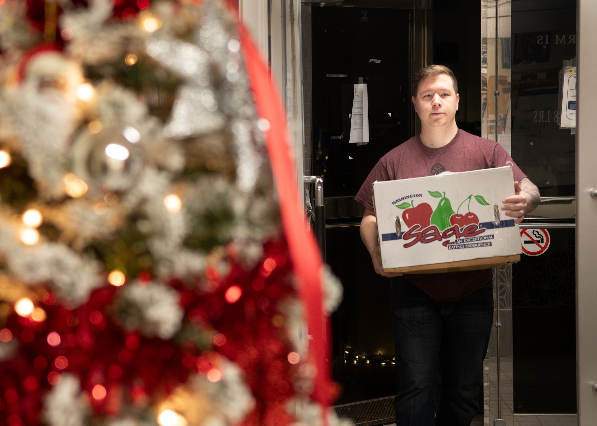 A man carrying a box of gifts walks into a building.