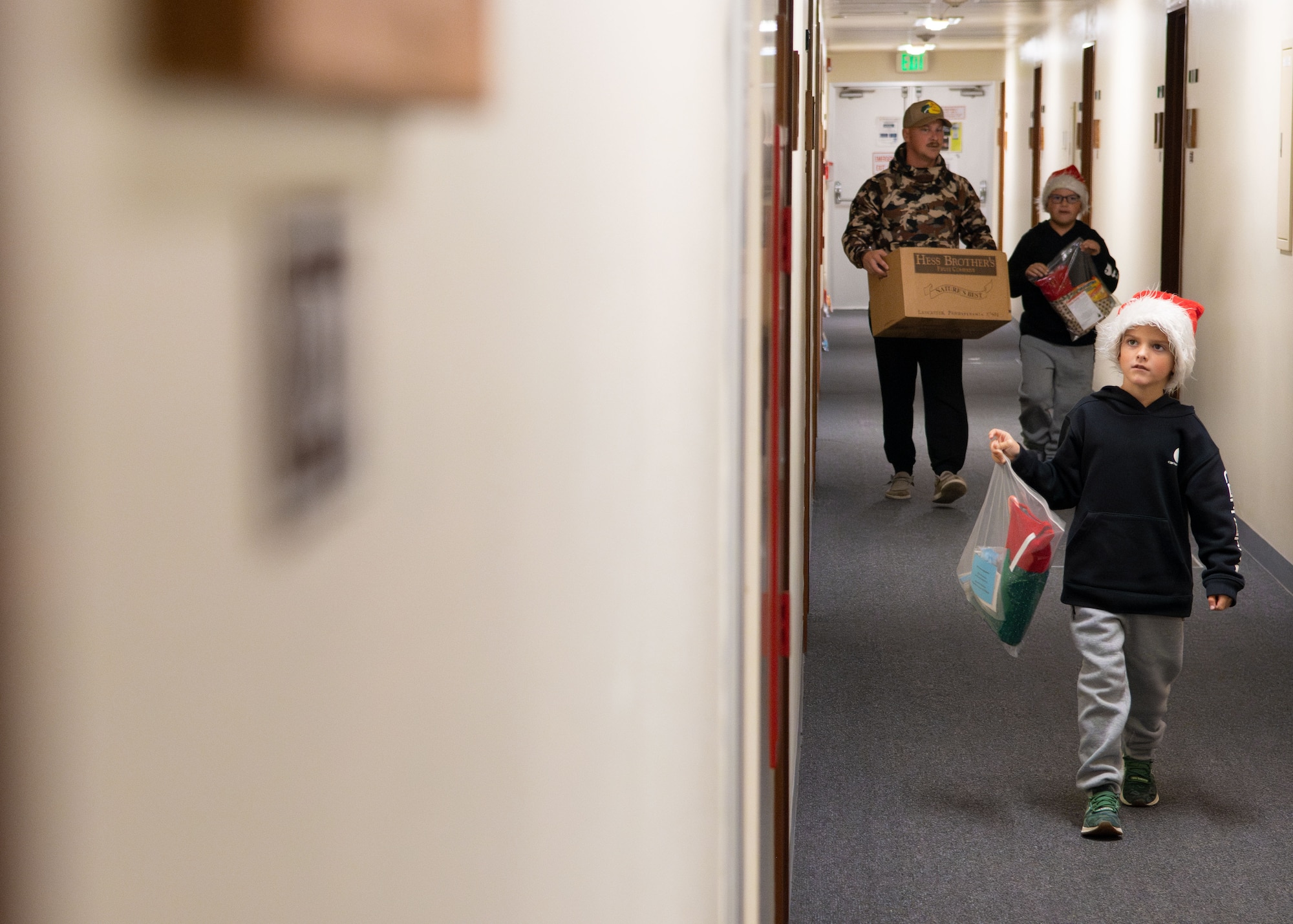 A man and his children walk through a hallway.