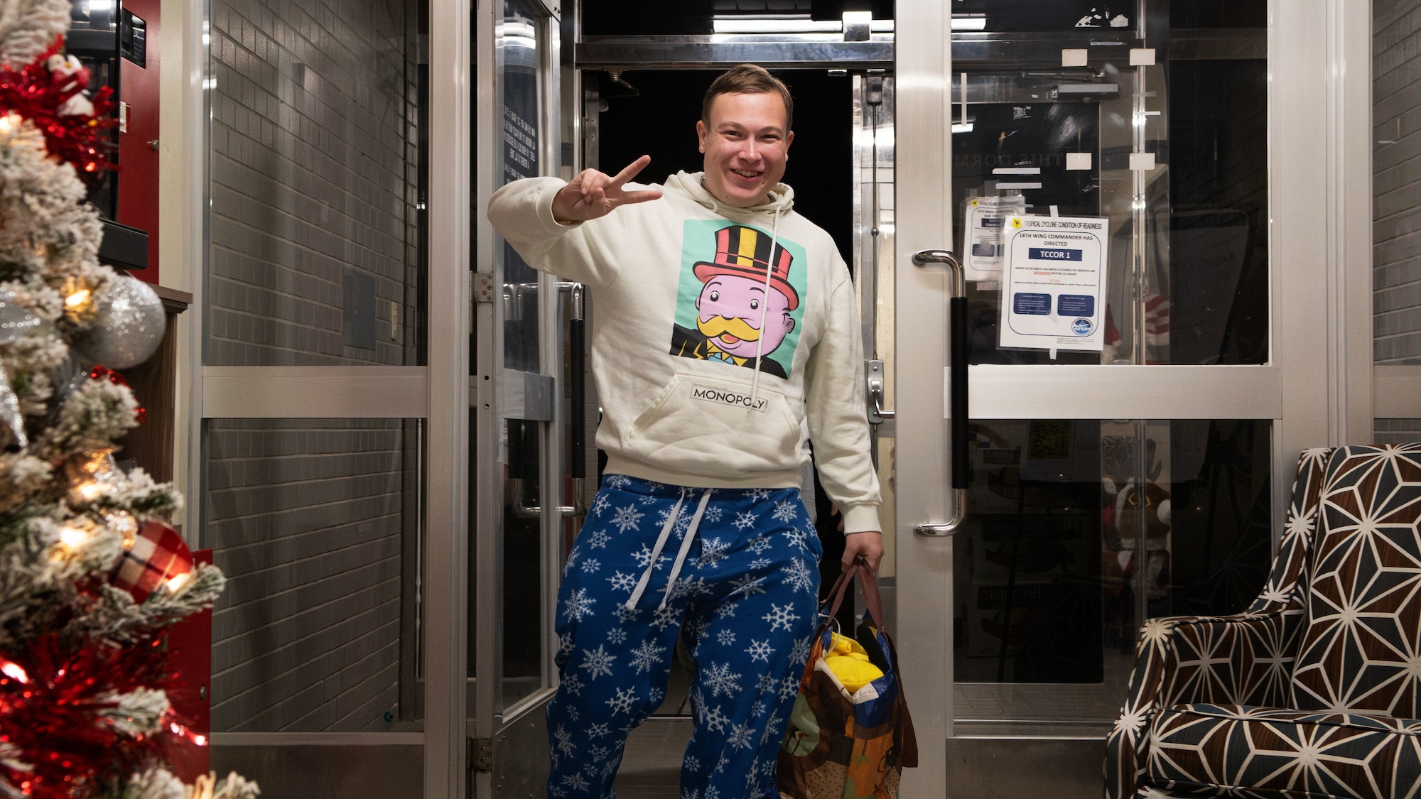 A man gives a peace sign while walking into a building.