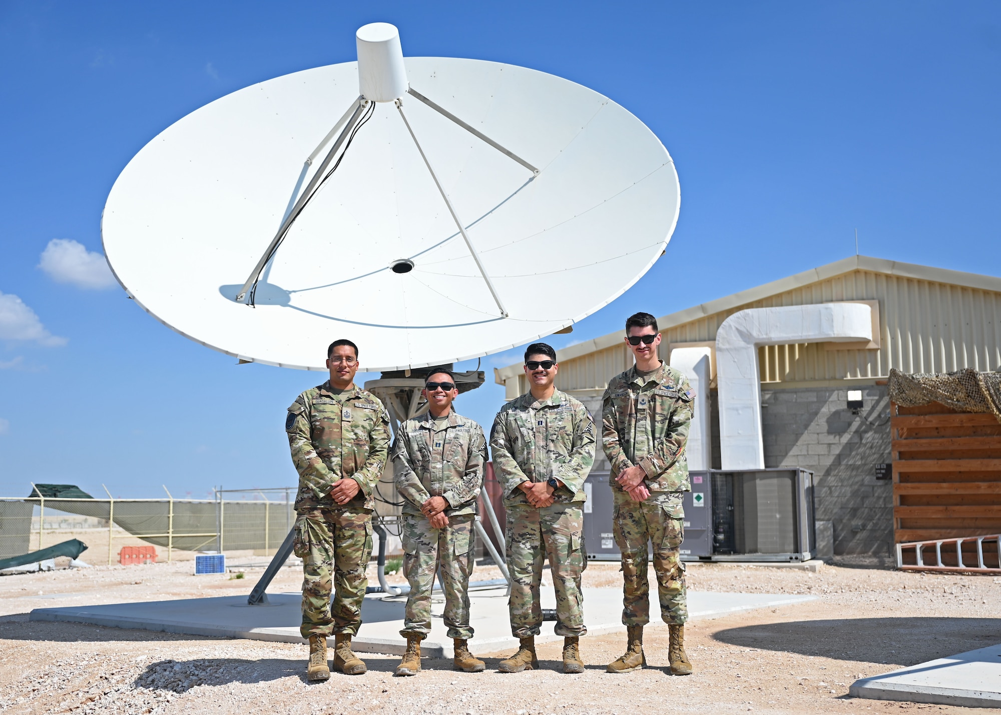 U.S. Space Force members assigned to the 5th Space Warning Squadron Detachment 2 gather for a group photo in front of a ground antenna at an undisclosed location in the U.S Central Command area of responsibility, Oct. 27, 2023. Members stationed as part of Detachment 2 are constantly working and training to ensure they uphold the safety of the service members deployed to these geographic combatant commands by ensuring timely reaction to incoming threats. (U.S. Air Force photo by Senior Airman Sarah Williams)