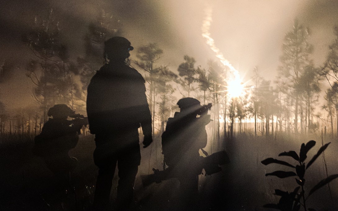 U.S. Marines with 3rd Battalion, 2d Marine Regiment, 2d Marine Division scan for targets as a flare lights up the field during the Marine Corps Combat Readiness Evaluation (MCCRE) on Camp Lejeune, North Carolina, Dec. 13, 2023. The MCCRE involves a range of scenarios and challenges that test the unit's ability to plan, coordinate, and execute complex missions, including offensive and defensive operations, logistics, and communications. (U.S. Marine Corps photo by Pfc. Eric Valerio)