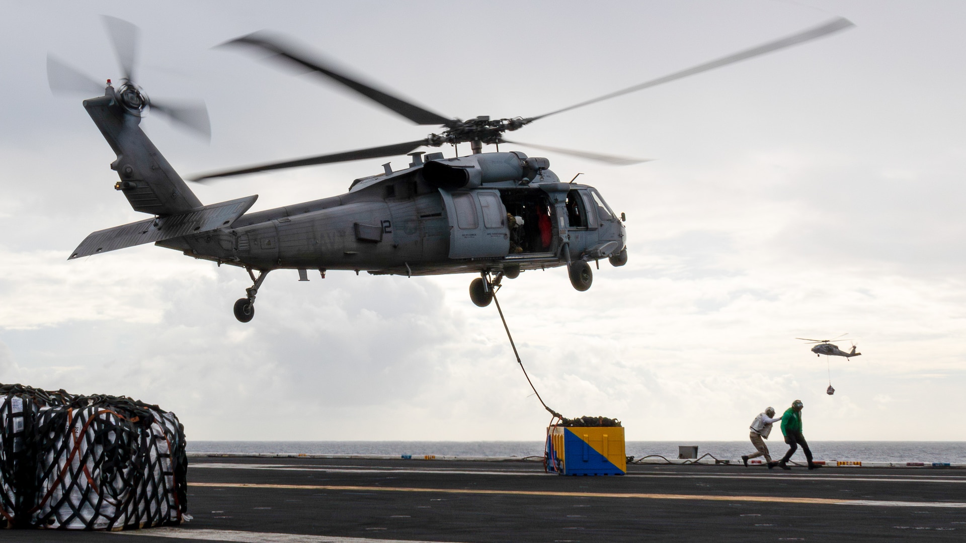 231215-N-TD381-1184 SOUTH CHINA SEA (Dec. 15, 2023) An MH-60S Sea Hawk, assigned to the “Black Knights” of Helicopter Sea Combat Squadron (HSC) 4, transports cargo onto the flight deck of Nimitz-class aircraft carrier USS Carl Vinson (CVN 70) during a replenishment-at-sea with Lewis and Clark-class dry cargo ship USNS Wally Schirra (T-AKE-8). Vinson, flagship of Carrier Strike Group ONE, is deployed to the U.S. 7th Fleet area of operations in support of a free and open Indo-Pacific. (U.S. Navy photo by Mass Communication Specialist 2nd Class Isaiah B Goessl)