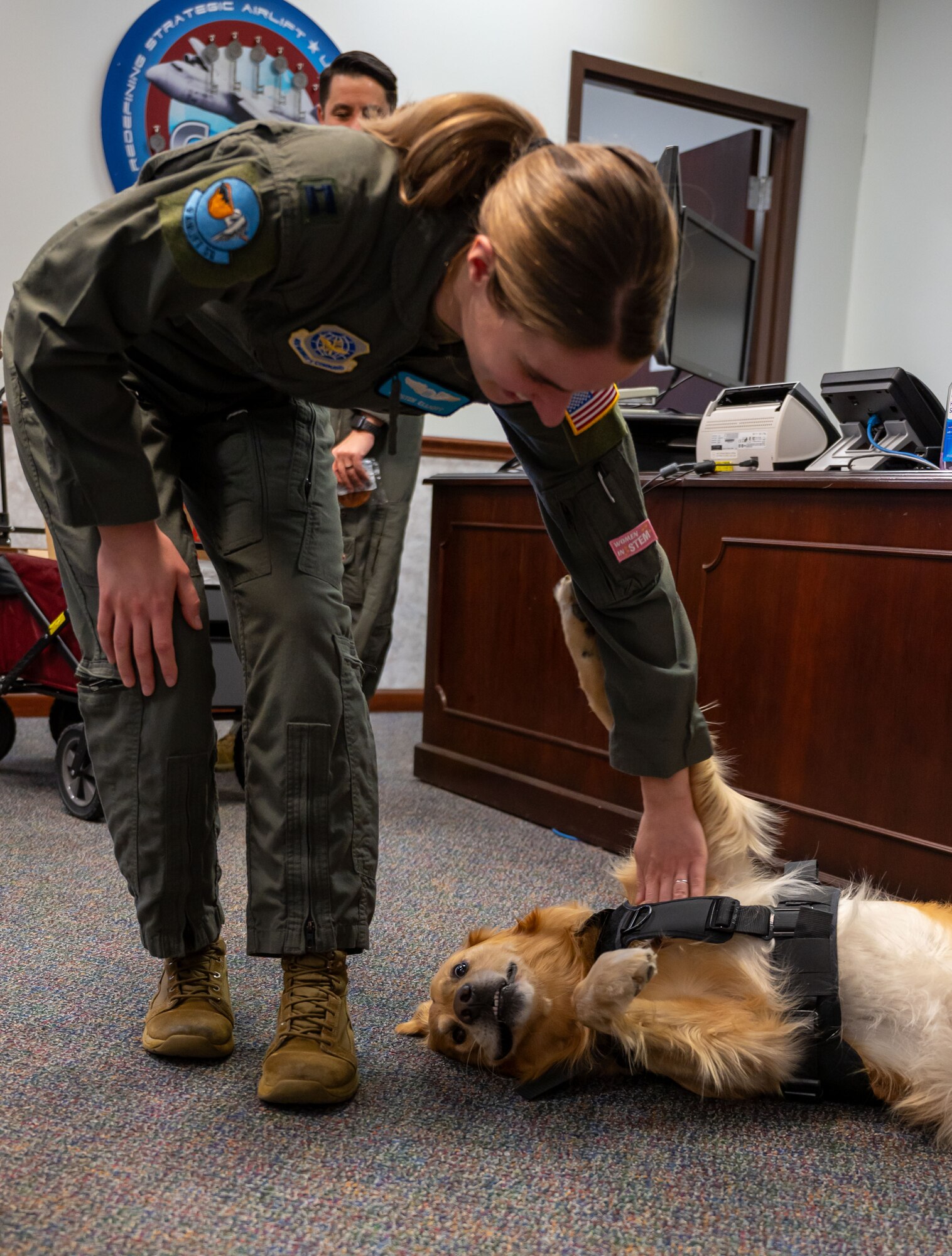 U.S. Air Force Capt. Kirsten Elliott, 9th Airlift Squadron pilot, pets Ranger Matthews, USO of Delaware emotional support dog, during Operation Cookie Drop at Dover Air Force Base, Delaware, Dec. 19, 2023. The Dover AFB Chapel and USO of Delaware delivered more than 3,000 cookies provided by Team Dover members to Airmen across the base. (U.S. Air Force photo by Airman 1st Class Amanda Jett)