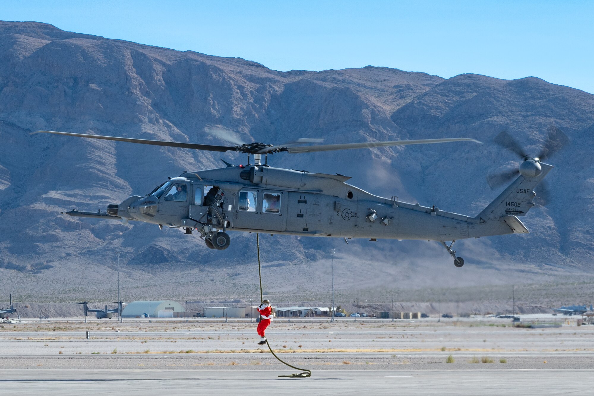 U.S. Air Force Chief Master Sgt. Jared Pietras, Senior Enlisted leader of the United States Air Force Weapons School (USAFWS), dresses up as Santa Clause and ziplines down an HH-60W at Nellis Air Force Base, Nevada, Dec. 9, 2023.