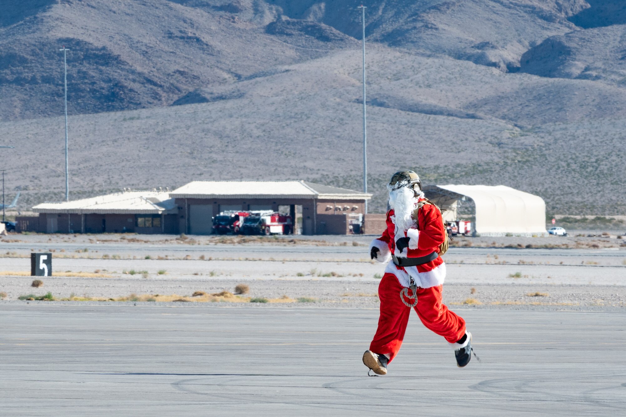 U.S. Air Force Chief Master Sgt. Jared Pietras, Senior Enlisted leader of the United States Air Force Weapons School, dresses up as Santa Clause and runs across the taxiway at Nellis Air Force Base, Nevada, Dec. 9, 2023.