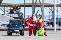 U.S. Air Force Chief Master Sgt. Jared Pietras, Senior Enlisted leader of the United States Air Force Weapons School (USAFWS), dresses up as Santa Clause and reprimands Lt. Col. Adam Clift, the Grinch, for trying to steal the sack of presents at Nellis Air Force Base, Nevada, Dec. 9, 2023.