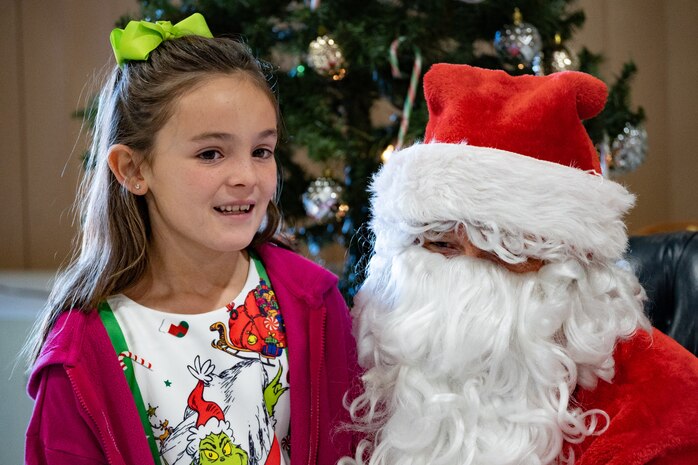 A young girl tells U.S. Air Force Chief Master Sgt. Jared Pietras, Senior Enlisted leader of the United States Air Force Weapons School dressed as Santa Clause, her Christmas wish list at the United States Air Force Weapons School (USAFWS) children’s holiday party at Nellis Air Force Base, Nevada, Dec. 9, 2023.