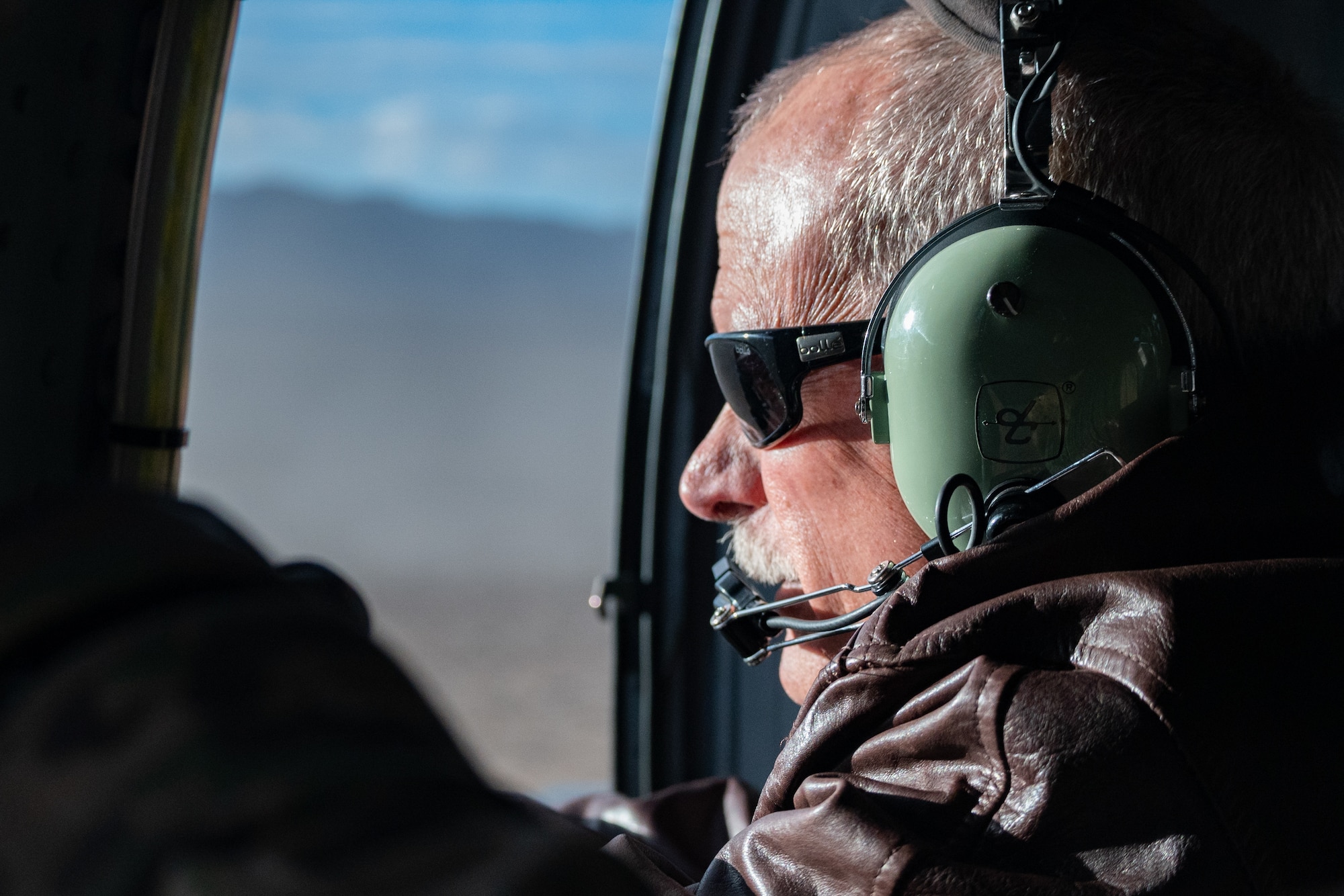 Thomas McGrath, vice president of the Air Force Association Thunderbird Chapter and president of the National Marine Corps Business Network, fires a .50 caliber machine gun on the HH-60W Jolly Green II as part of the 53rd Wing Civic Leader flight at the Nevada Test and Training Range, Nevada, Dec. 12, 2023.