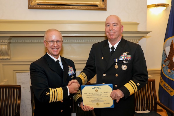 Adm. Daryl Caudle, commander, U.S. Fleet Forces Command, left, presents Vice Adm. William Houston, right, with the Distinguished Service Medal during the Commander, Submarine Forces change of command ceremony onboard Naval Station Norfolk, Dec. 28.