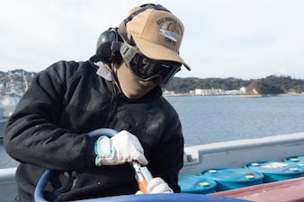 Aviation Boatswain’s Mate (Aircraft Handling) Airman Recruit Derrick Yaotse, from Los Angeles, uses a needle gun for corrosion control on the flight deck aboard the U.S. Navy’s only forward-deployed aircraft carrier, USS Ronald Reagan (CVN 76), while in-port Commander, Fleet Activities Yokosuka, Dec. 27.