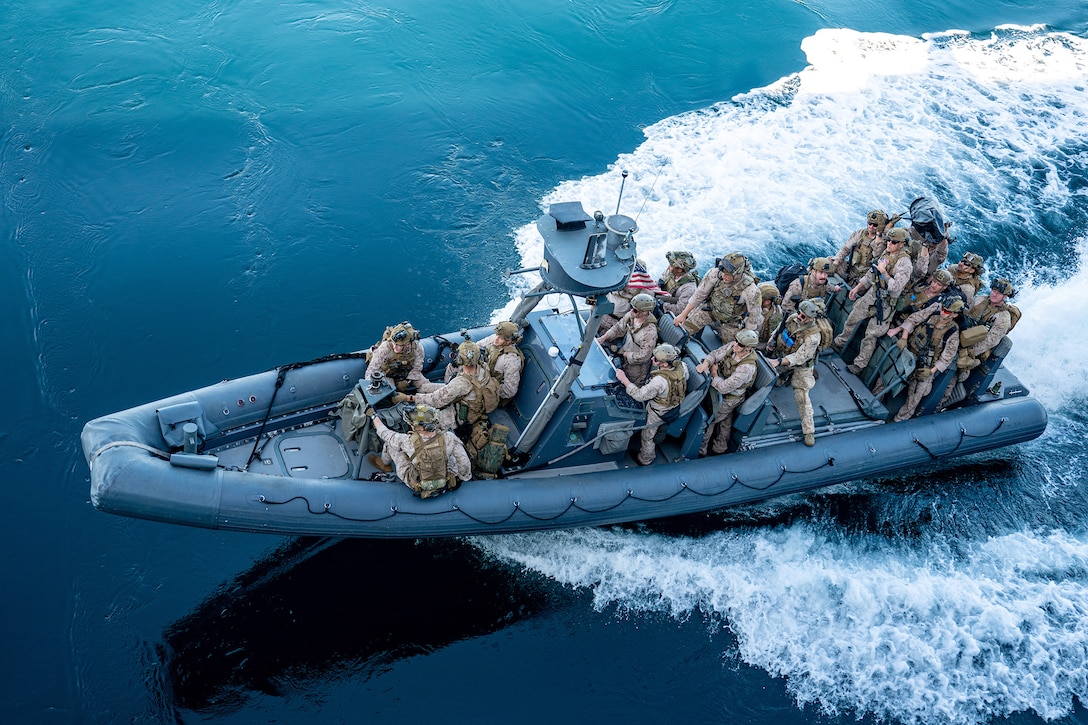 At least 20 Marines sail in an inflatable boat in open water during training.