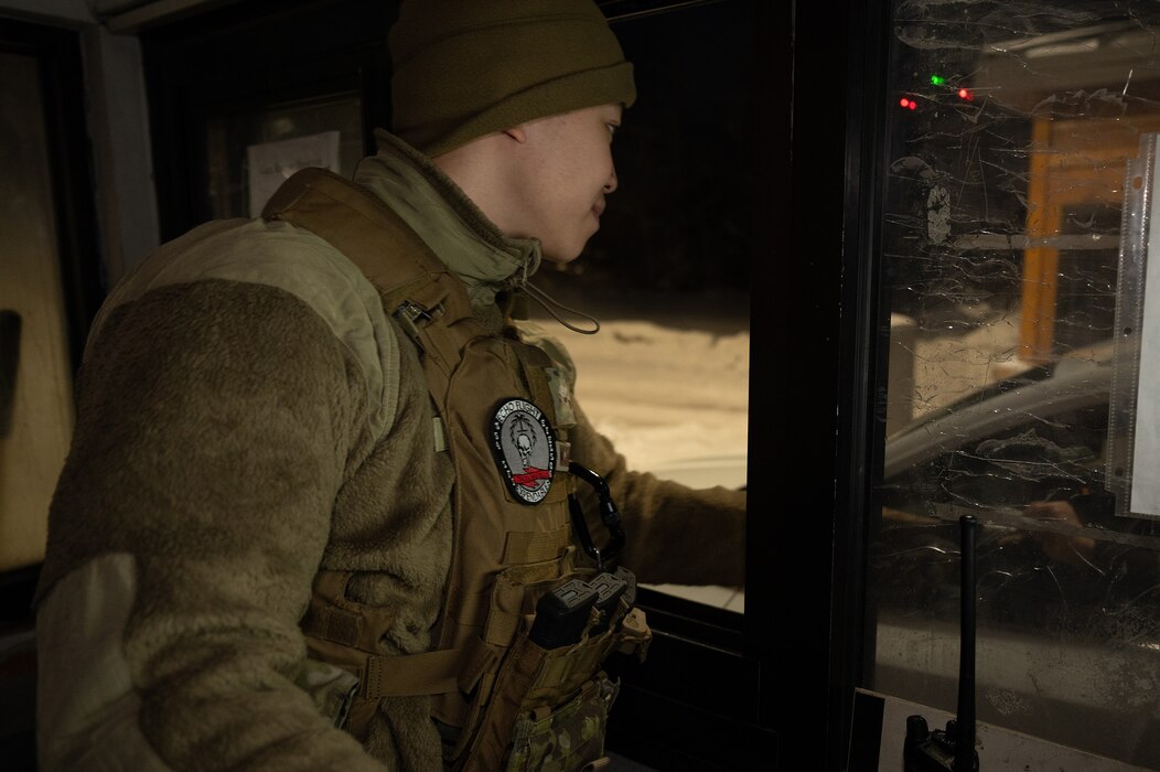 U.S. Air Force Airman Albert Nguyen, 354th Security Forces Squadron installation entry controller, stands by to check identification at the main gate on Eielson Air Force Base, Alaska, Dec. 27, 2023. The 354th SFS provides law enforcement and security services while safeguarding the base and transient aircraft. (U.S. Air Force photo by Airman Spencer Hanson)
