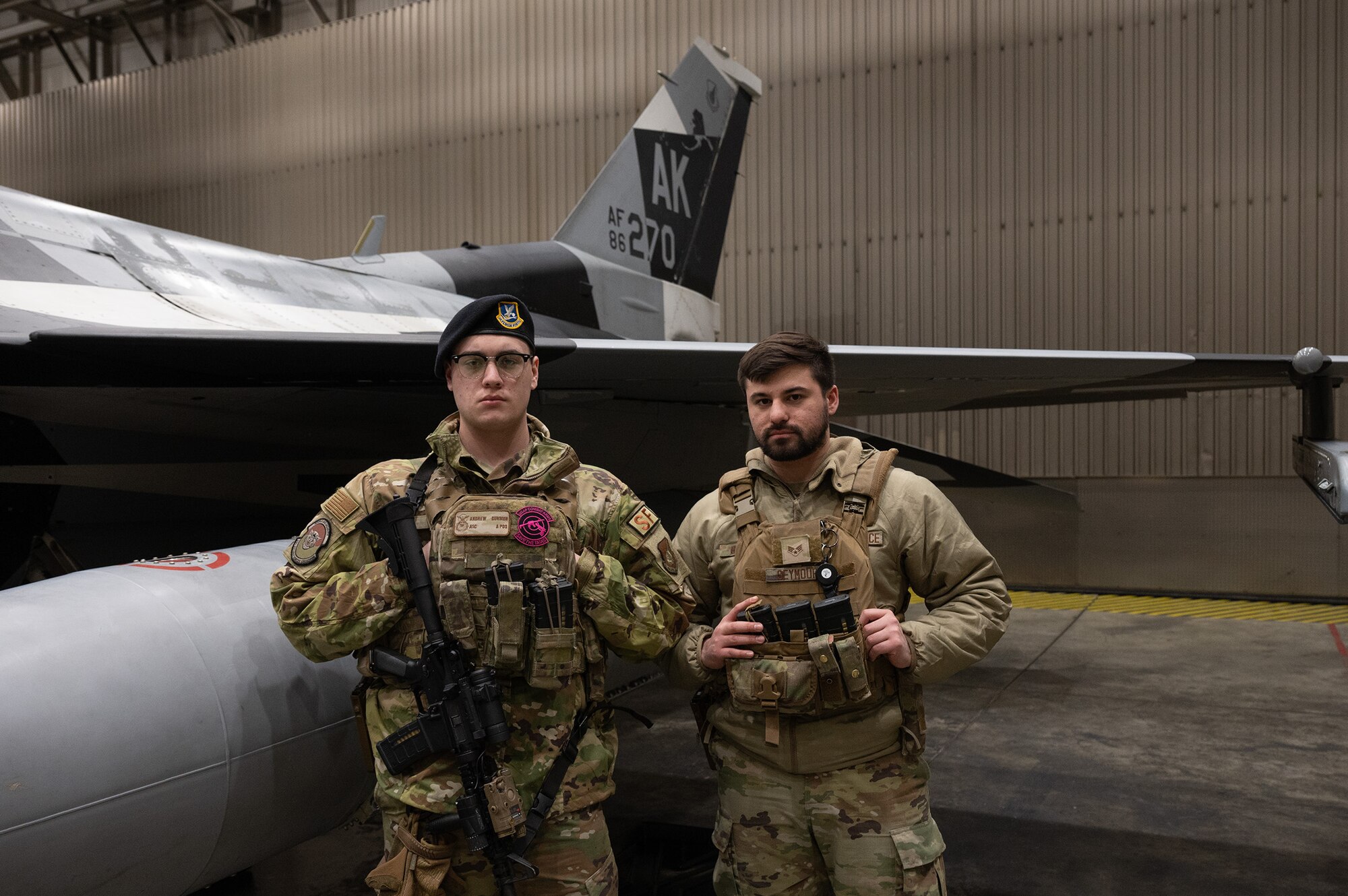 U.S. Air Force Airman 1st Class Andrew Dunmon (left) and Senior Airman Tyson Seymour, 354th Security Forces Squadron installation entry controllers, guard an F-16 Falcon hangar on Eielson Air Force Base, Alaska, Dec. 27, 2023. As the largest career field in the Air Force, security forces has a variety of different duties such as law enforcement and security services. (U.S. Air Force photo by Airman Spencer Hanson)