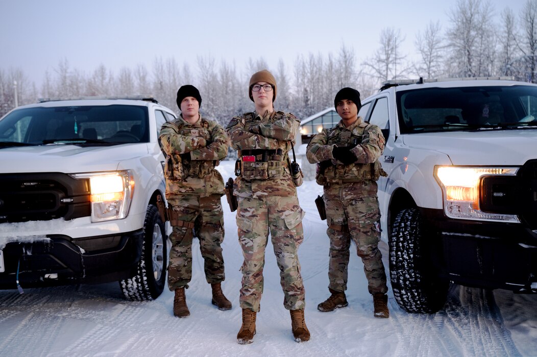 U.S. Air Force Staff Sgt. Jake Magalhaes-Pachico (left), 354th Security Forces Squadron flight chief, Senior Airman Allyson Bleecker (middle), 354th SFS installation entry controller, and Staff. Sgt Lemuel Magalhaes-Pachico (right), a 354th SFS flight chief, pose for a photo with their patrol vehicles on Eielson Air Force Base, Alaska, Dec. 27, 2023. As the largest career field in the Air Force, security forces have a variety of different duties such as law enforcement and security services. (U.S. Air Force photo by Airman Spencer Hanson)