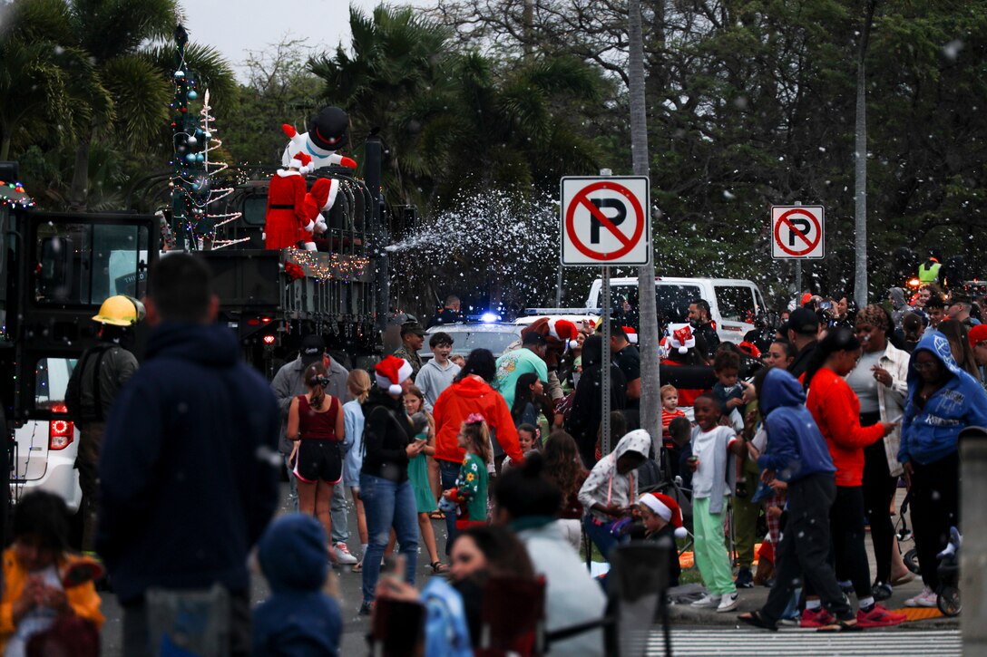 Families gather to watch the Santa Parade, Marine Corps Base Hawaii, Dec. 19, 2023. The parade, which consisted of volunteers from PMO, United Service Organizations, Aircraft Recue and Firefighting, Explosive Ordnance Disposal, Federal Fire Department, Base Safety Department and other organizations, made several stops across the installation to pass out candy and spread holiday cheer. (U.S. Marine Corps photo by Lance Cpl. Hunter Jones)