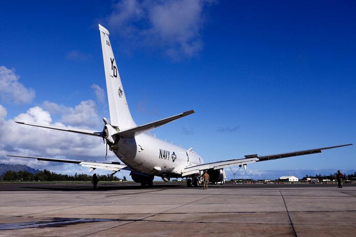 U.S. Navy Sailors tow a U.S. Navy P-8A Poseidon to a designated wash area after extraction from waters just off the runway at Marine Corps Air Station Kaneohe Bay, Marine Corps Base Hawaii, Dec. 4, 2023. The aircraft was relocated in preparation for decontamination of any potential foreign substances as well as salt water from its exterior. U.S. Navy Sailors and Marines worked with local and off-island specialists to recover the structurally intact P-8A Poseidon on Dec. 2, 2023; environmental protection measures were set in place, including 24/7 monitoring, containment booms, absorbent material, and a skimmer on standby during extraction. (U.S. Marine Corps photo by Lance Cpl. Hunter Jones)