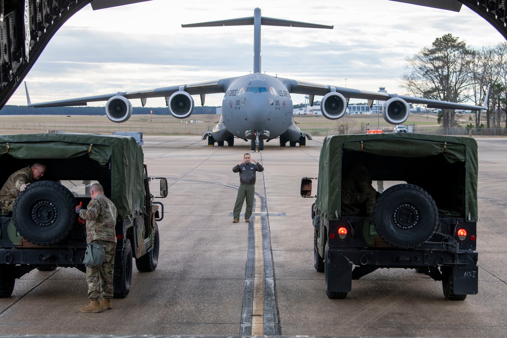 Tech. Sgt. Jerad Easterling, from the 172nd Operations Group, center, marshals a truck carrying medical personnel away from the tail of a C-17 Globemaster III aircraft on Jan. 28, 2023, in Jackson, Mississippi. This was part of a large-scale readiness exercise to test the capabilities of Mississippi Air National Guard Airmen in a contested environment.