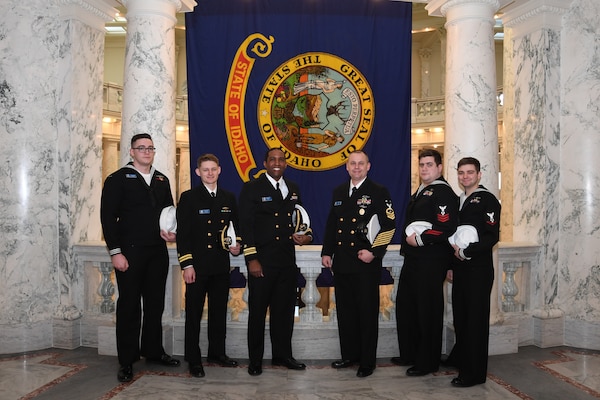 Crewmembers from the future USS Idaho (SSN 799) pose in front of the Idaho state flag during a tour of the capital building in Boise, Idaho, Jan. 25.